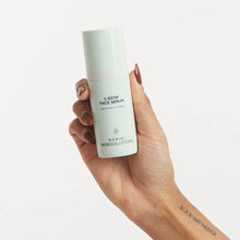 Load image into Gallery viewer, Hand holding a bottle of C-Esta Face Serum by Marini Skinsolutions on a white background