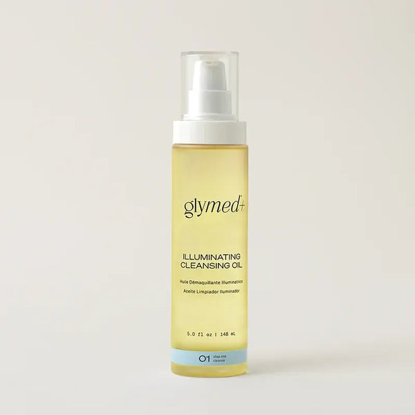 A bottle of glymed+ Illuminating Cleansing Oil on a light beige background. The bottle is made of frosted clear plastic showing the pale yellow oil inside, with a white pump dispenser and a light blue accent band at the bottom.