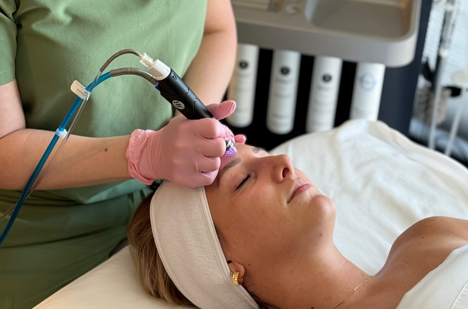 Person receiving a facial treatment with a device in a clinical setting