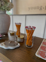 Pencils in glass containers on a wooden surface with decorative elements.
