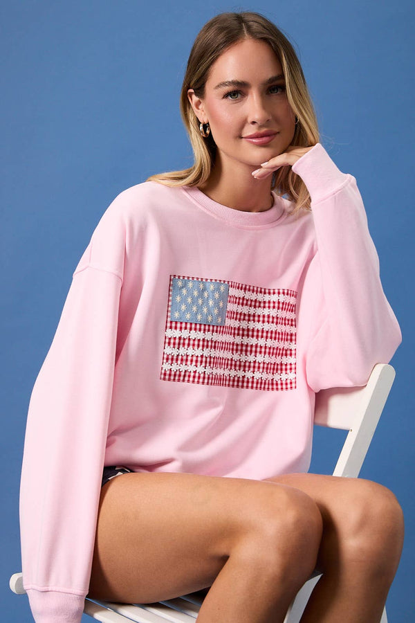 Woman wearing a pink sweatshirt with an American flag design on a blue background